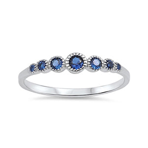 Delicate silver ring embellished with seven round cut dark blue cubic zirconia stones. The largest stone sits in the centre of the band, and each stone either side becomes gradually smaller than the last.